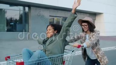 快乐的女孩朋友骑着购物车在<strong>商场</strong>附近的<strong>户外</strong>大笑